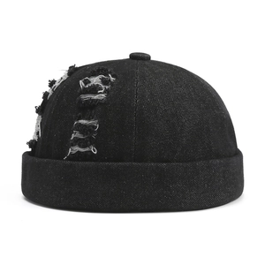 Gros plan sur un bonnet docker en denim noir avec détails déchirés et bord roulé