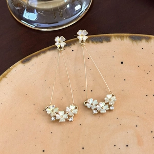 Dettaglio orecchini pendenti a fiori con petali effetto conchiglia e strass luminosi