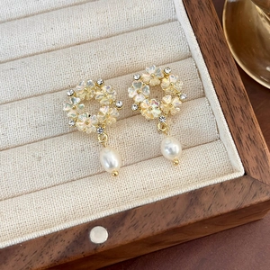 Dettaglio di orecchini floreali con strass e perle a goccia su espositore per gioielli