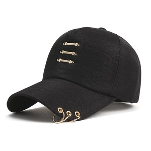 Detail of black baseball cap with three gold metal rings and bars in punk street style