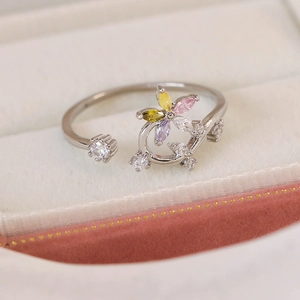 Macro detail of silver-tone open ring with multi-color zircon flower on velvet box