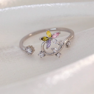 Macro shot of silver ring featuring a multi-colored floral zircon cluster and silk backdrop