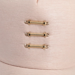 Pink baseball cap featuring three parallel gold metal ring details on the fabric