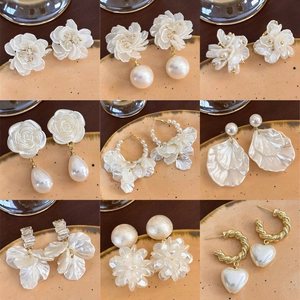 Elegante collezione di orecchini con perle bianche e petali di conchiglia in nove stili
