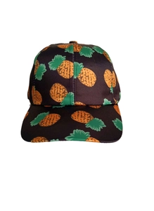 Detail of the vibrant pineapple print on a black baseball cap with tropical summer style