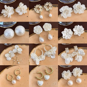 Set di 12 eleganti orecchini placcati oro con perle e fiori su un piatto in ceramica decorata
