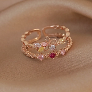 Macro shot of rose gold double-layer floral ring with colorful zircons on champagne satin