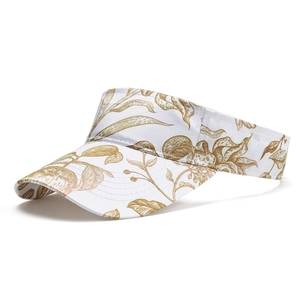 Detail view of white sun visor with tropical golden leaf print and precise stitching