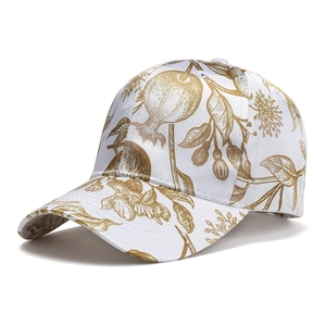 Close-up of white cotton baseball cap with gold pomegranate embroidery and curved brim