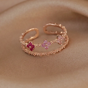 Detail view of double-layer rose gold ring with zircon flowers on silk background