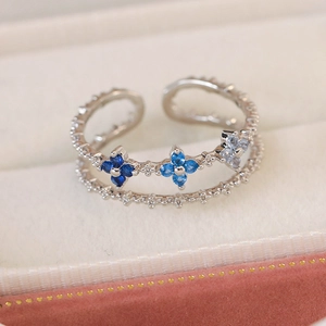 Detail of a double-layer silver ring with blue zircon clover flowers on white velvet