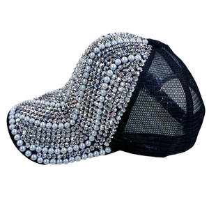 Vue détaillée des strass argentés et des perles blanches sur une casquette en maille noire