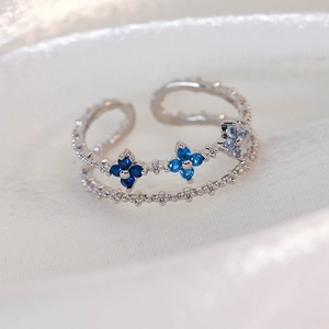 Macro detail of silver double-layer open ring with blue gradient zircon flowers