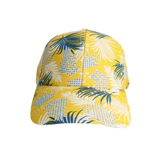 Detail of yellow baseball cap featuring blue tropical leaf patterns on cotton canvas fabric