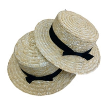 Détail de chapeaux de paille avec large ruban noir à nœud et design à sommet plat