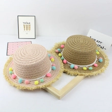 Détail de chapeaux de soleil en paille avec pompons colorés et bordures à franges