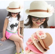 Détail d'un chapeau de soleil enfant en paille tressée avec grande fleur en mousseline