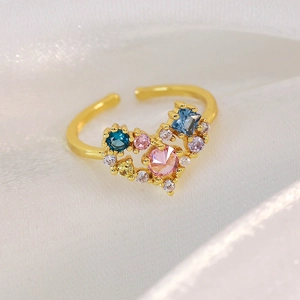Detail of heart ring with multi-colored cubic zirconia on a white silk background