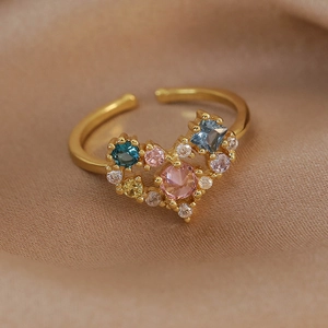 Detailed macro view of heart shaped gold ring with colorful zircon stones on silk fabric