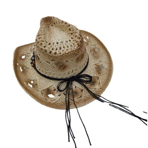 Détail d'un chapeau de cowboy en paille tressée beige avec bord ajouré et pompons en perles