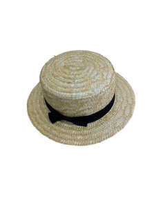 Détail d'un chapeau de soleil en paille avec ruban noir et texture tissée concentrique