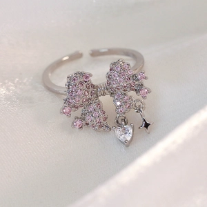 Macro detail of adjustable silver ring with pink zircon bow and heart star charms
