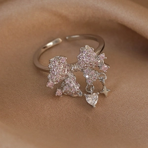 Detail of silver bow ring with pink zircon and dangling heart and star charms