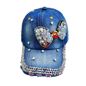 Blue denim baseball cap with rhinestone bow decoration and distressed frayed brim edges