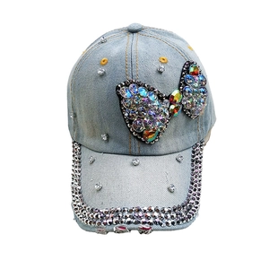 Light blue denim baseball cap with rhinestone bow and distressed details on the brim