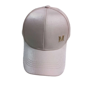 Detailed macro view of light pink satin baseball cap with rhinestone M metal emblem