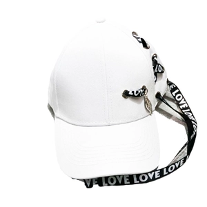 Détail d'une casquette blanche avec anneaux métalliques et ruban noir à breloques argentées