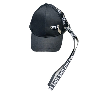 Détail de la casquette noire avec anneaux métalliques, pendentif feuille et ruban LOVE