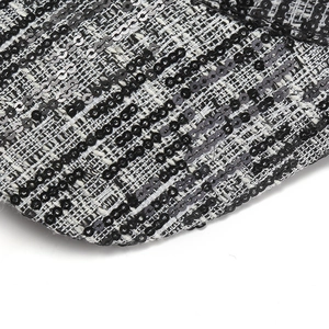 Macro detail of the woven tweed texture and shiny black sequins on the baseball cap
