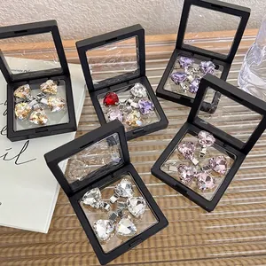 Set of heart-shaped crystal hair clips in pink and gold displayed in black floating boxes
