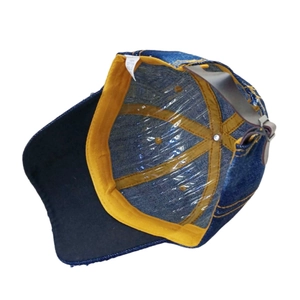 Detail view of the interior denim baseball cap showing the cotton label and yellow sweatband