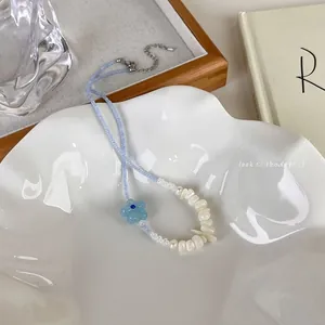 Vue détaillée du collier de perles à fleurs bleues sur un plateau en céramique