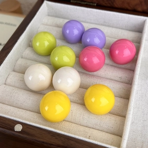 Orecchini colorati a bottone in resina dai toni caldi esposti in una scatola portagioie in legno
