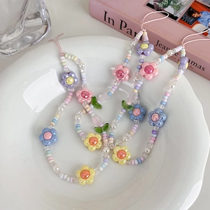 Détail de bijoux de téléphone faits main en perles macaron avec tulipes sur plateau