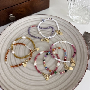Détail de bracelets en pierres colorées et perles d'eau douce avec breloques cœur sur plateau