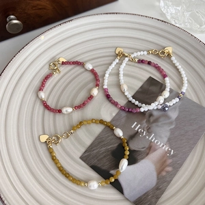 Vue détaillée de trois bracelets perlés avec perles d'eau douce et breloques cœur or