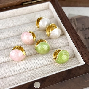 Three pairs of French-style gold enamel hoop earrings in pink, white, and green on wood tray