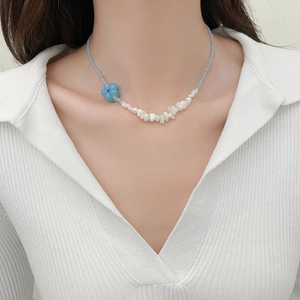 Détail du collier de perles bleues avec perle fleurie et perles baroques blanches