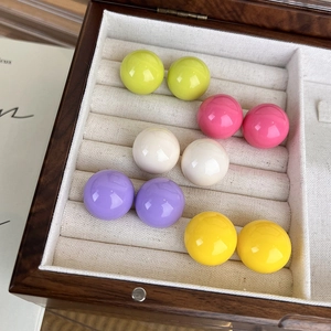 Dettaglio di orecchini a lobo in resina colorata in una scatola regalo in legno e velluto