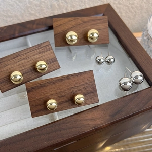 Ensemble de boucles d'oreilles boules dorées et argentées polies dans une boîte en bois