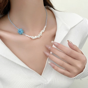 Détail du collier de perles à fleurs bleues et coquillages naturels sur un mannequin