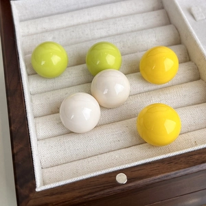 Primo piano di orecchini a bottone colorati in un vassoio portagioie in velluto beige
