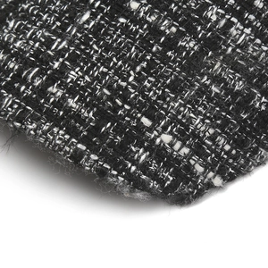 Close-up of premium black and white woven tweed fabric texture with natural frayed edges