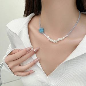 Vue détaillée du collier de perles bleu clair avec perles baroques blanches et fleur bleue