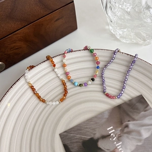 Gros plan de trois bracelets colorés en pierres et perles sur une assiette en céramique