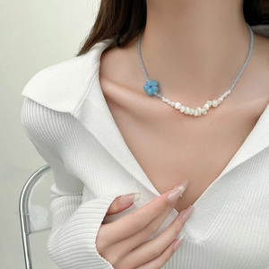 Détail du collier de plage perlé avec fleur bleue et fragments de coquillages blancs